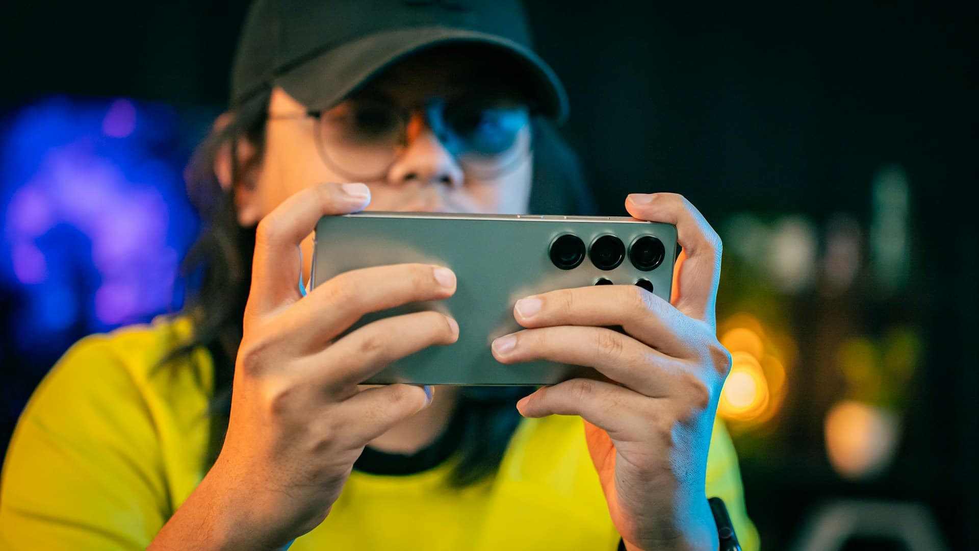 A woman in a yellow shirt is holding a camera