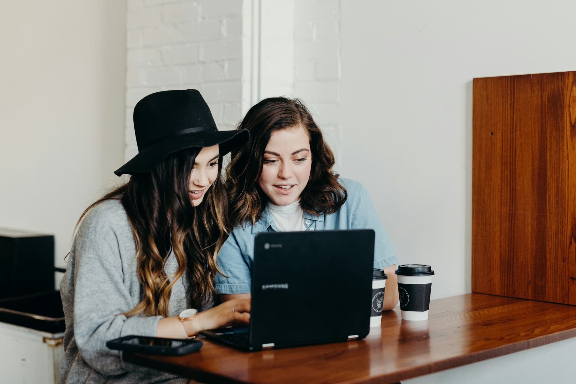 Two women sitting near a table using a laptop